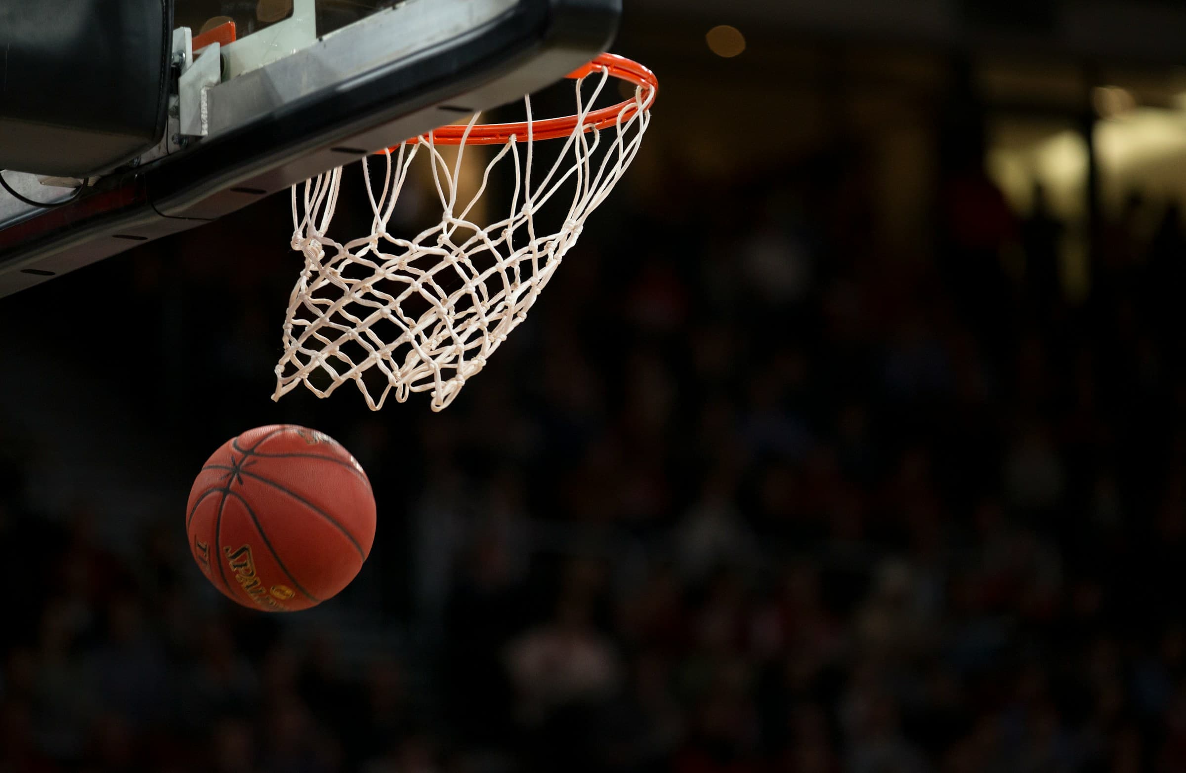 Basketball dropping through a hoop's net during a game