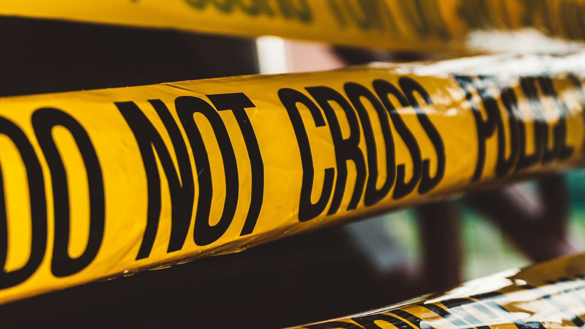 Close-up of layered yellow 'DO NOT CROSS POLICE' crime scene tape