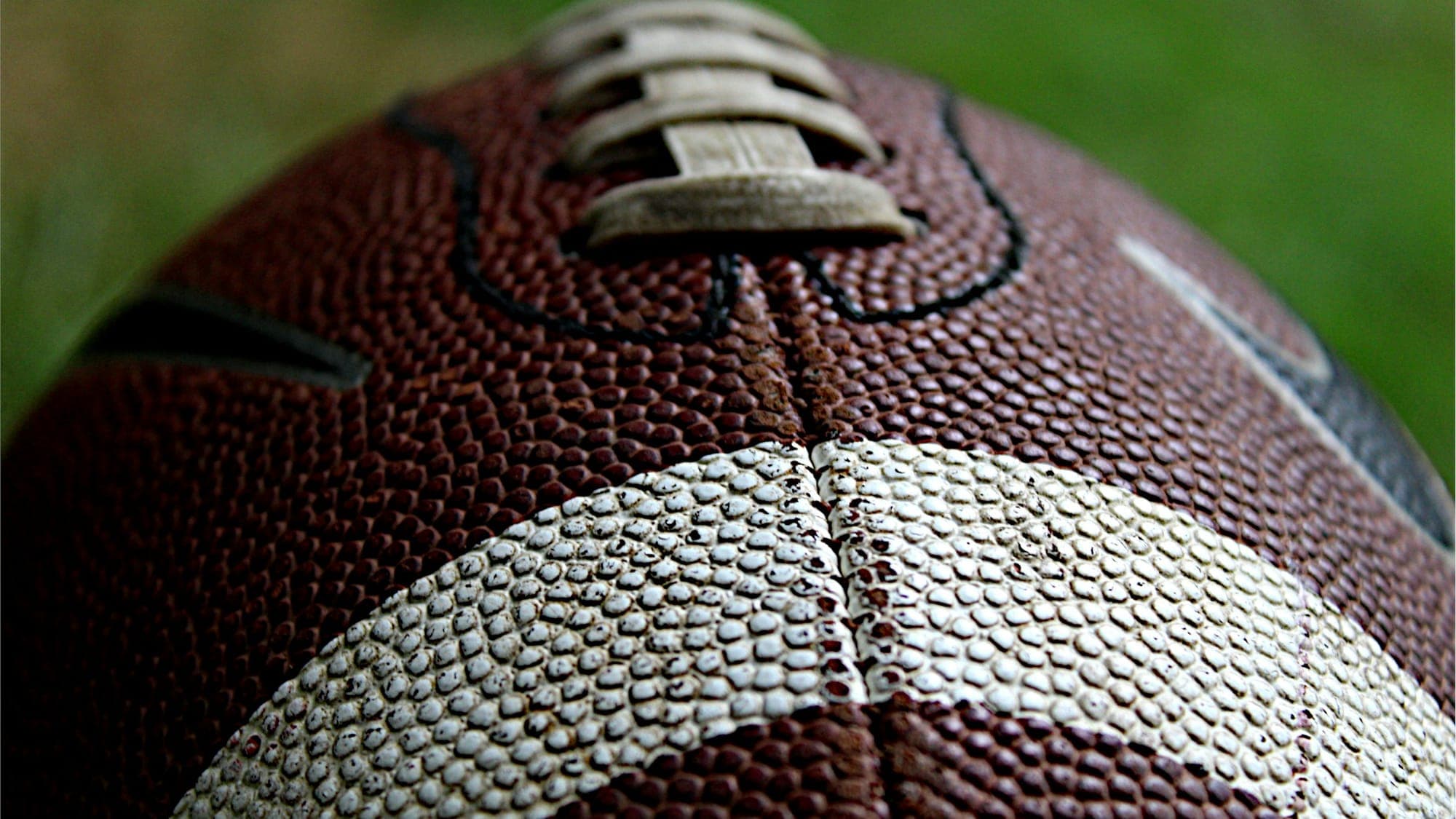 Close-up of a red and white leather football resting on a grass field